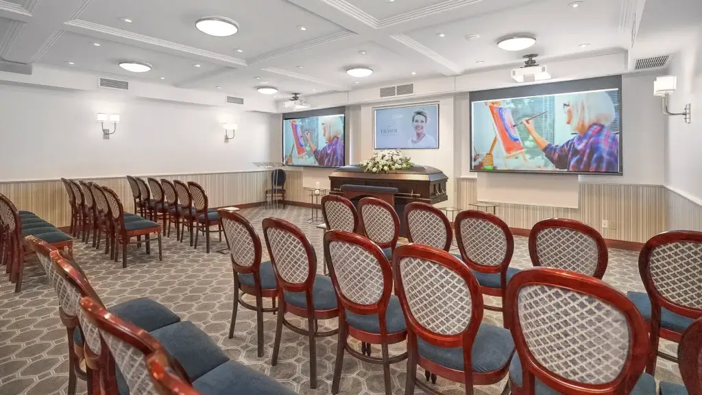 Chapel at Kane Fetterly Funeral Home in Montreal set up for a funeral service with casket, floral tribute, and video tribute screens