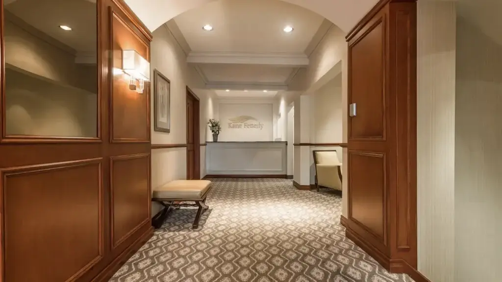 Entrance corridor leading to the reception area at Kane Fetterly Funeral Home in Montreal, featuring warm lighting and elegant wood finishes