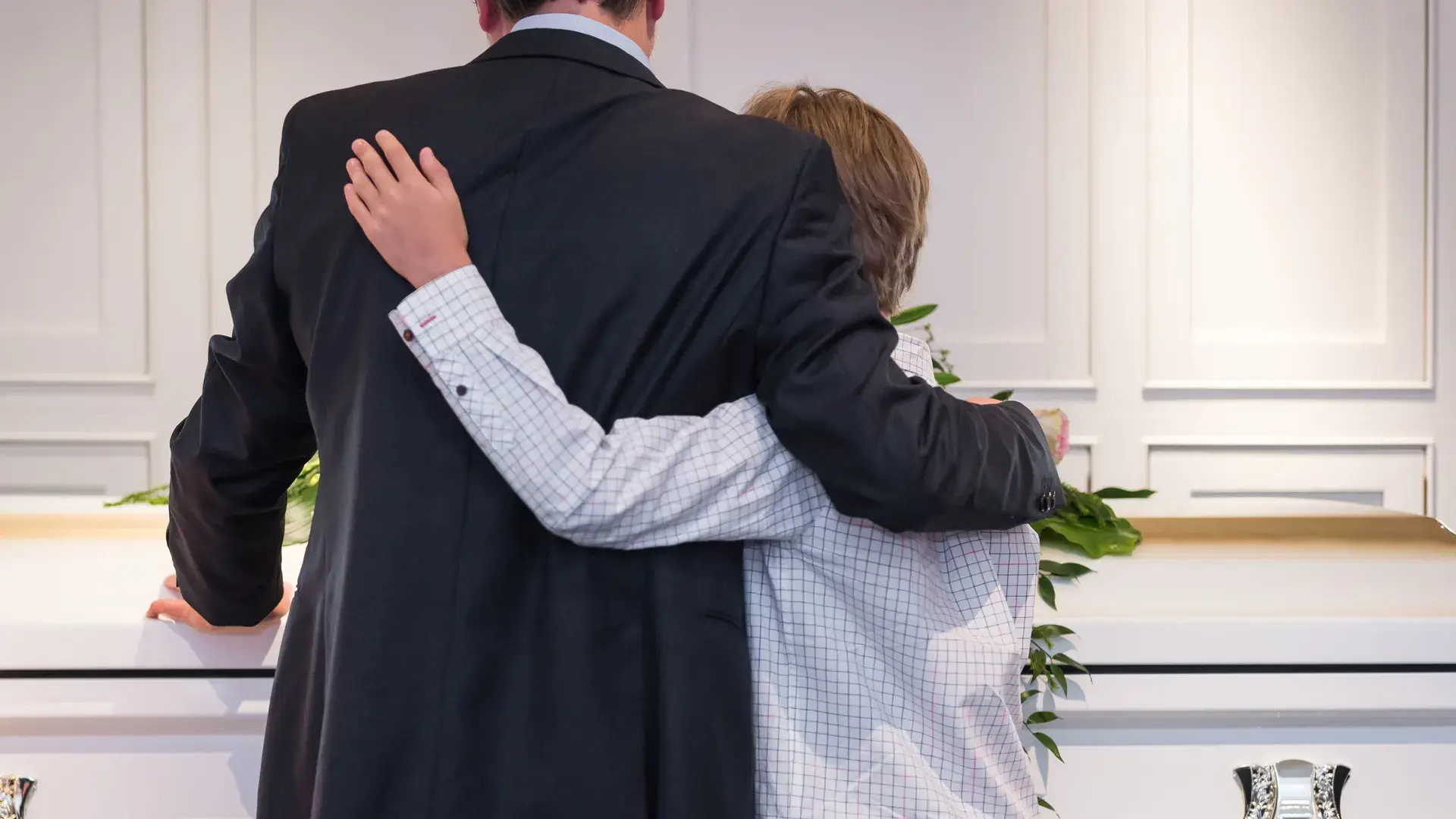 Grieving child embracing parent near a casket, symbolizing family comfort, support, and remembrance at Kane Fetterly Funeral Home in Montreal