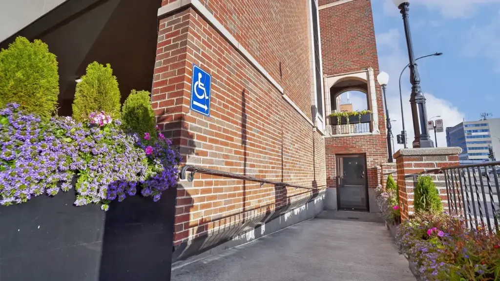 Wheelchair-accessible ramp with flowers at the side entrance of Kane Fetterly Funeral Home in Montreal