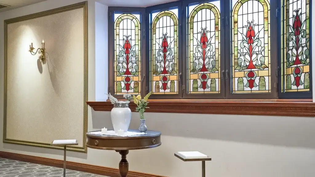 Urn display at Kane Fetterly Funeral Home in Montreal arranged near stained-glass windows with candles and flowers