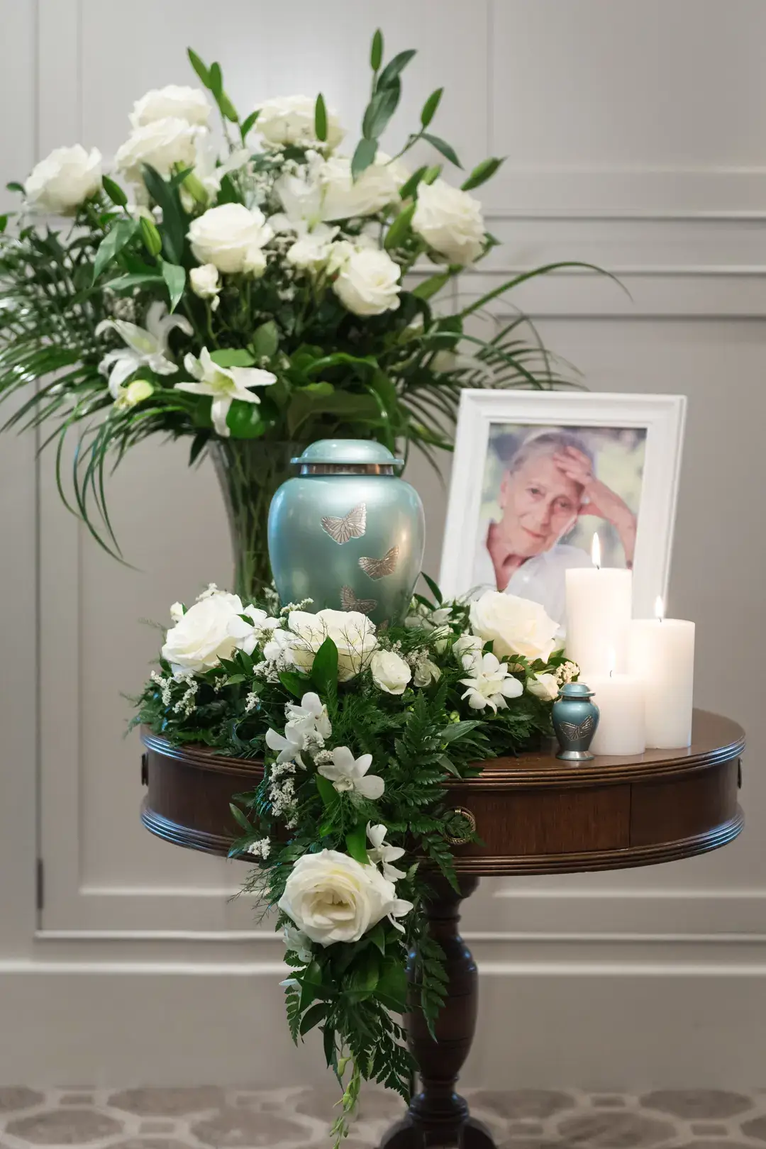 Memorial service with urn, white flowers, candles, and a framed photo, at Kane Fetterly Funeral Home in Montreal