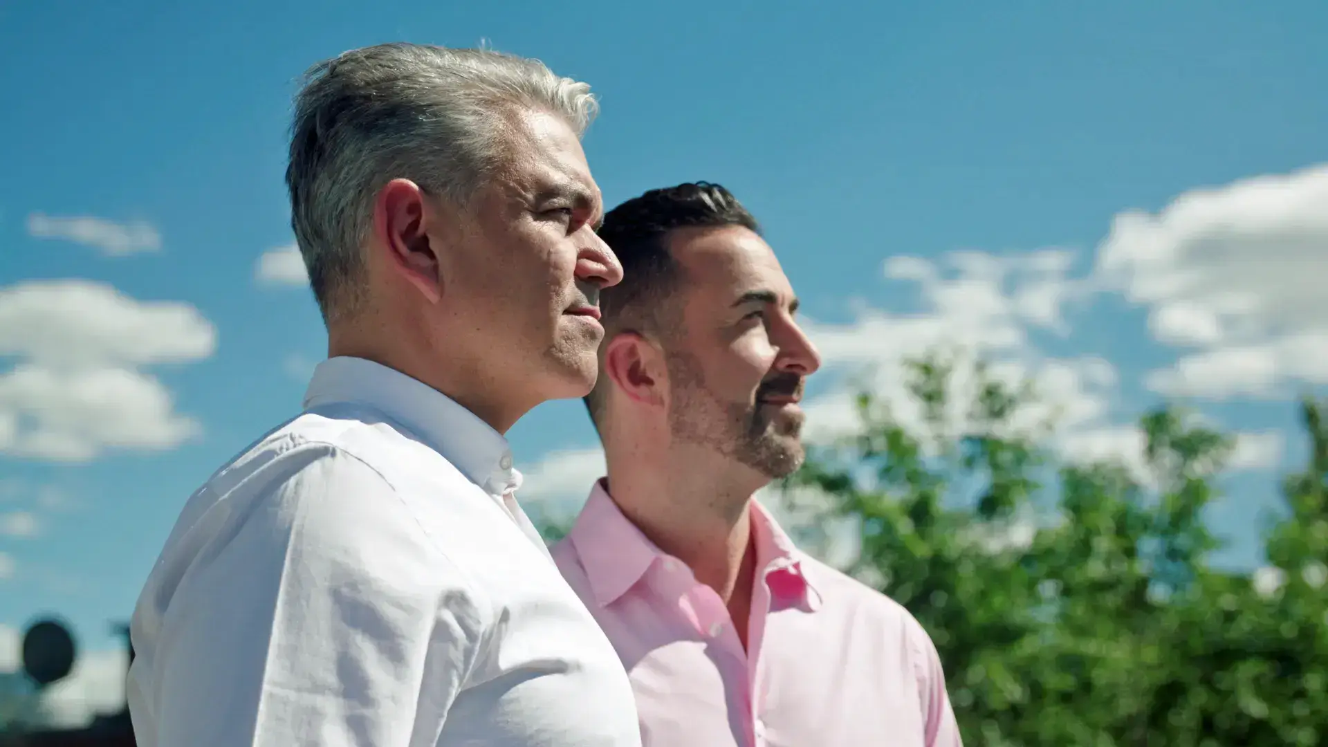 Couple standing outdoors under a bright sky.
