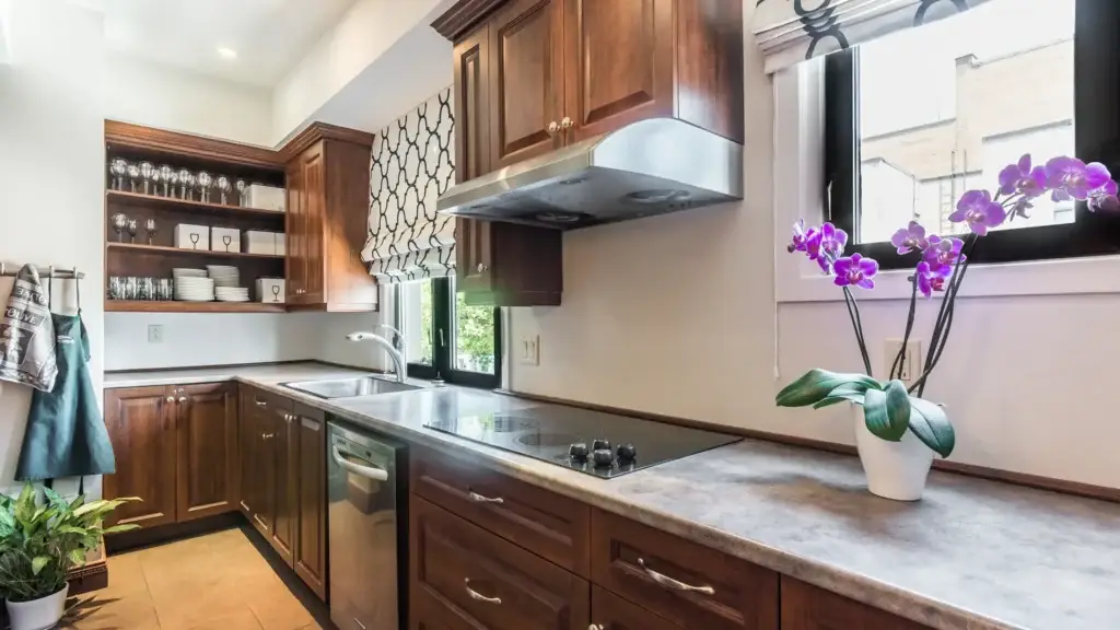 Reception kitchen area at Kane Fetterly Funeral Home in Montreal with warm wood cabinetry, stainless-steel appliances, open shelving, and natural light for family gatherings